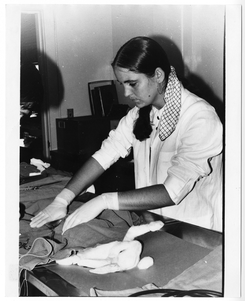 Woman in lab coat and lab gloves experiments with textiles
